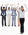 Smiling business team raising their arms with a woman in foreground against white background