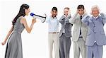 Woman yelling in a megaphone at business people with their hands over their ears against white background