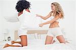 Pillow fight between two girls on a bed