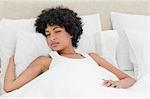 Curly haired woman waking up in a white bed