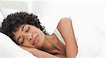 Schwarze behaarte Frau friedlich schlafend im Bett weiß