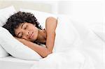 Frizzy haired woman sleeping deeply in a white bed