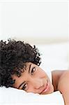 Portrait of a beautiful woman lying on her bed against white background