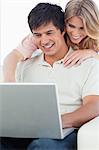 Un homme est à l'aide de l'ordinateur portable comme la femme lui regarde derrière sa tête.