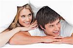 Man and woman smiling and resting their heads on their hands and looking to the side,