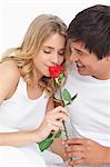 L'homme souriant veille la femme l'odeur de la rose comme ils ont tous deux maintenir.