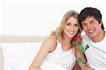 Homme et femme ensemble souriant comme ils regardent en face d'eux avec une rose à la main.