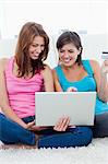 Heureuse jeunes femmes s'asseoir avec un ordinateur portable lors de vos achats sur internet