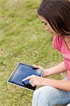 Jeune femme sérieuse, à l'aide de son ordinateur tablette dans la campagne