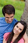 Jeune femme souriante, appuyé contre un arbre à côté de son petit ami charmant
