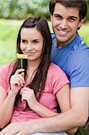 Jeune femme tenant une fleur en se tenant debout dans la campagne avec son petit ami