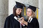 Jeune étudiant diplômé en prenant une photo d'elle-même et de son amie souriant