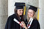 Junge glücklich Abschluss Mädchen Blick auf eine digitale Kamera und halten ihre Diplome
