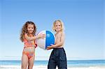 Jeunes frères et sœurs avec un ballon de plage, debout sur la plage