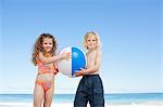 Jeunes frères et sœurs avec leurs commandes de ballon de plage sur la plage