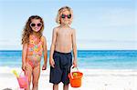 Little children with sunglasses standing on the beach