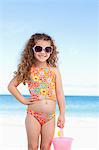Cute smiling little girl with sunglasses standing on the beach