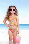 Cute smiling girl with her sunglasses standing on the beach