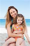 Smiling mother hugging her daughter on the beach