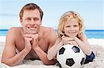 Glückliche Vater und Sohn mit dem Fußball am Strand liegen