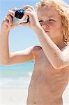Petit garçon avec une caméra numérique à la plage