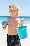 Smiling little boy with his bucket and shovel at the beach