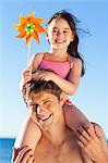 Smiling father at the beach with his little daughter on his shoulders