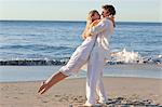 Young couple spinning at the beach during sunset