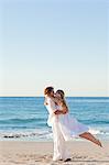 Young man spinning his girlfriend at the beach