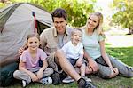 A smiling family together in the park beside their tent