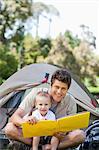 A smiling father and son hold a book while looking straight ahead