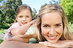 A close up shot of a mother and daughter lying on the ground as they look at the camera