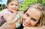 A side view of a smiling mother and daughter lying on the grass in the park