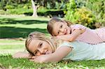 A side view of a mother lying on the ground with her daughter lying on her back