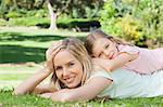 A mother with her daughter rests on her back rests her own head on her hand