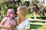 A smiling mother holding onto her daughter who has a pin-wheel in front of her face