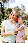 A mother sniffing the flower her daughter has asked her to smell