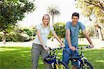 A smiling couple looking ahead with their bikes beside them