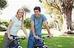 A couple on their bikes in the park smiling