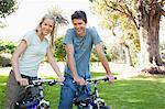 A smiling couple looking in front of them while on their bikes