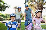 A smiling family in the park on their bikes as they get ready to go cycling