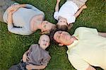 A sleeping family on the ground in the park their heads all by each other