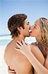Junge Menschen küssen einander stehen am Strand