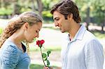 Vue latérale d'un jeune un homme donnant à sa petite amie une rose