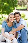 Happy young couple sitting on the lawn