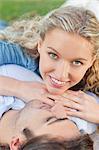 Smiling young woman laying on her boyfriend in the park