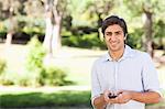 Smiling young man holding his cellphone in the park