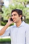 Smiling young man on his mobile phone in the park