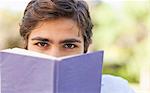 Young man hiding his face behind a book