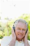 Close-up of a man smiling while using headphones to listen to music while sitting on a bench